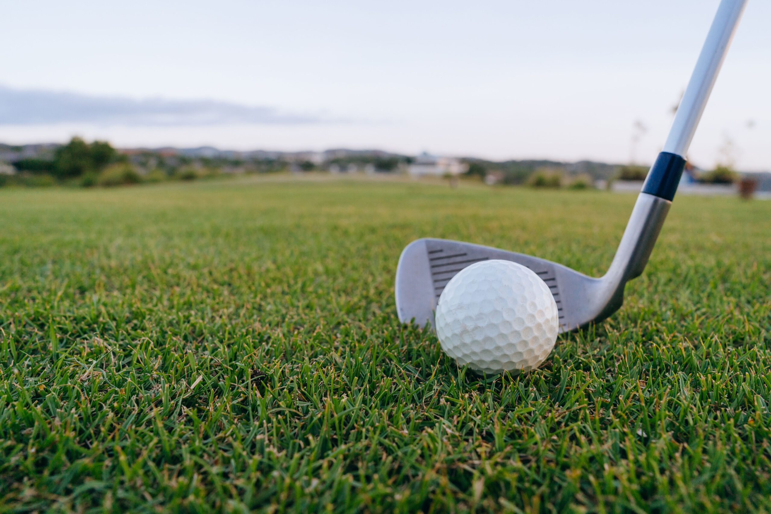 Close-up of a golf club head about to strike a golf ball for a hole-in-one shot.
