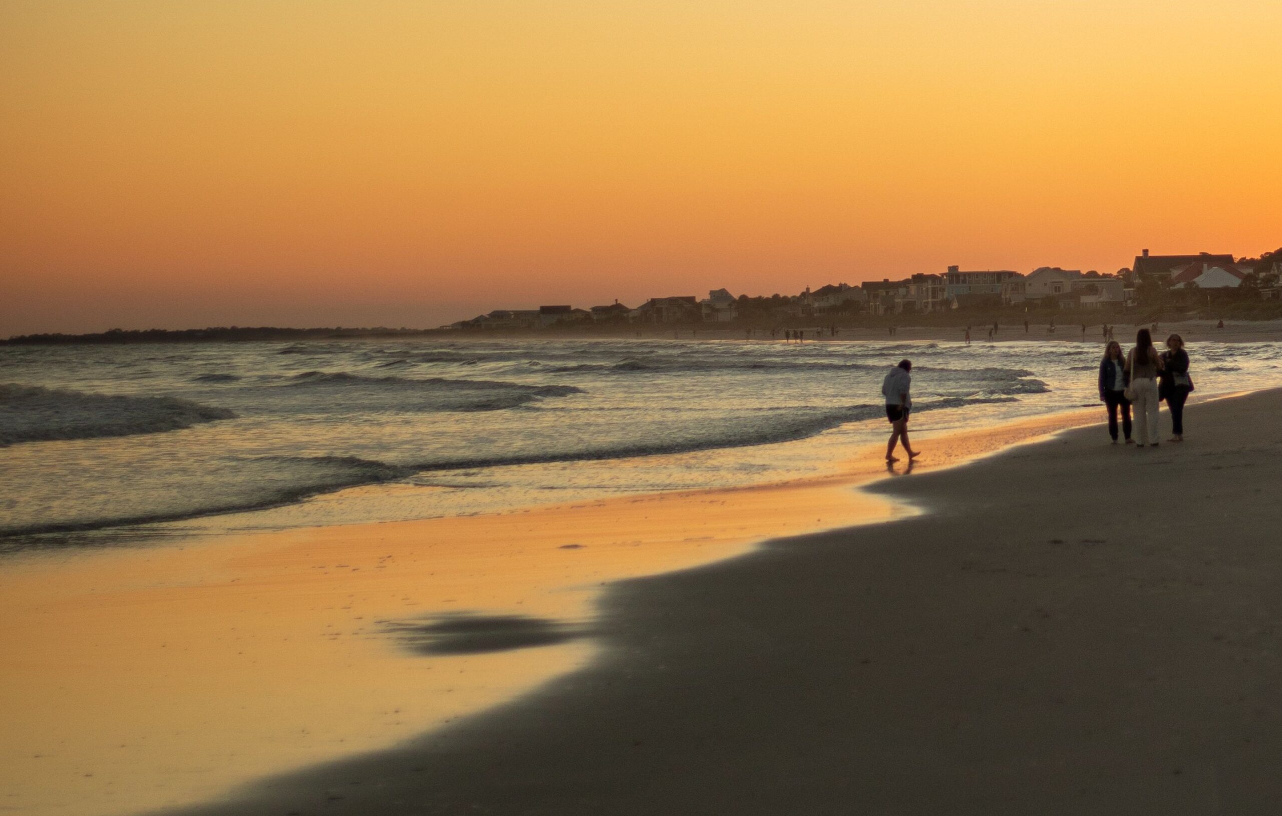 Beach sunset with several people along the shore.