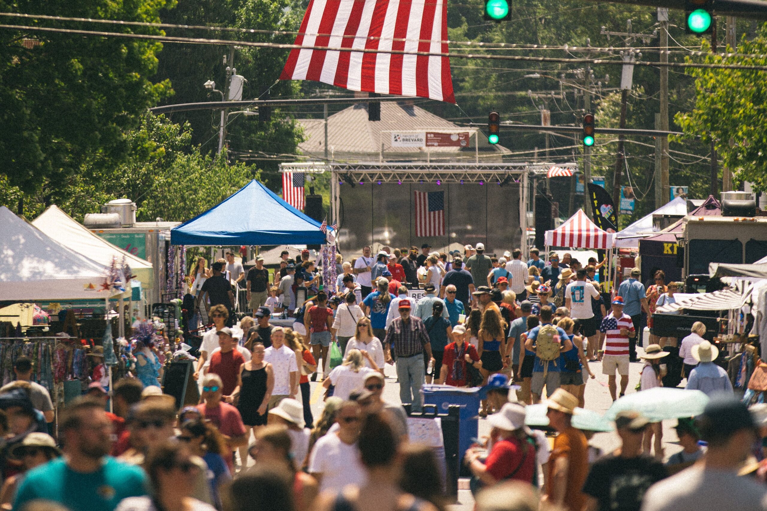 Large crowd gathered at an outdoor festival with several American flags visible throughout the scene.