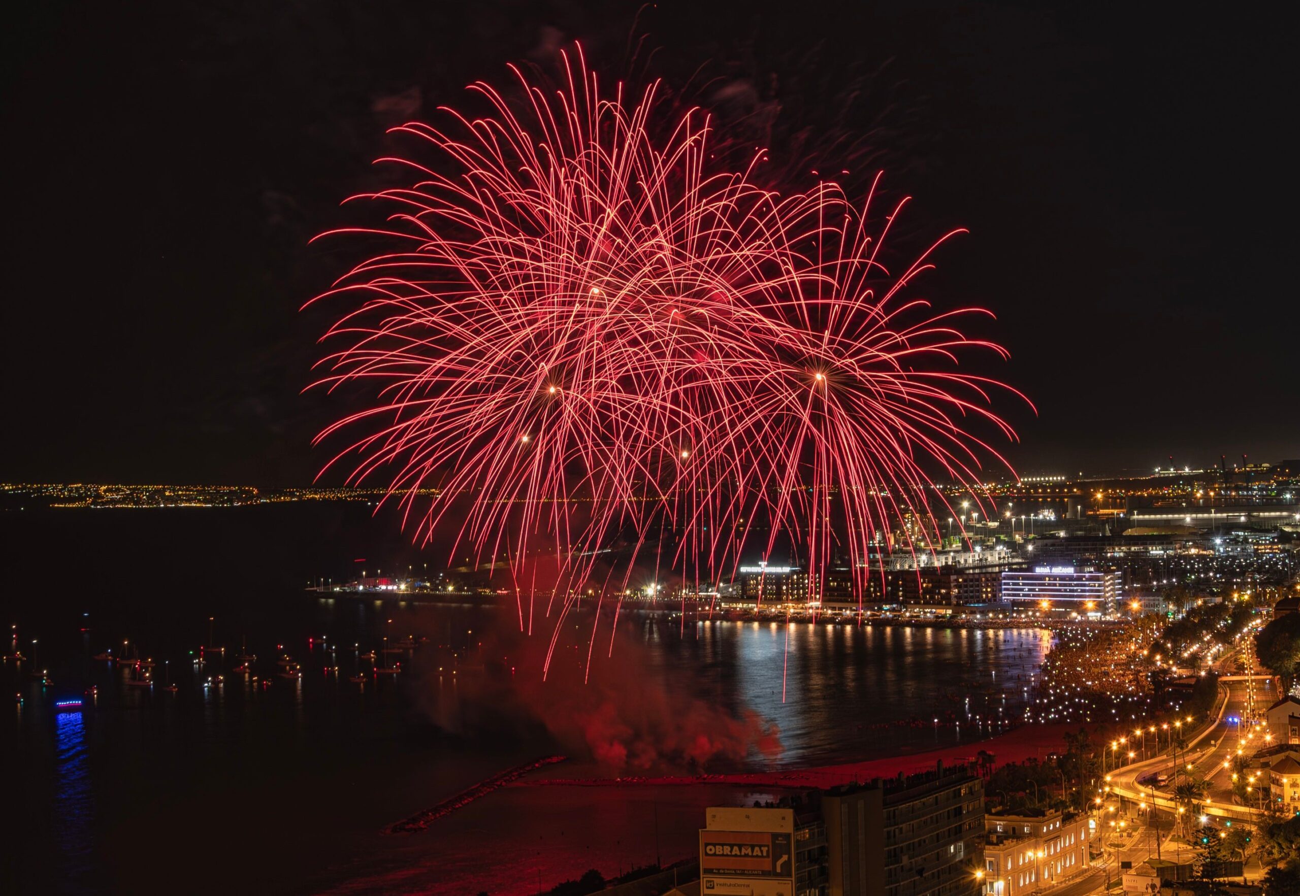 Red fireworks lighting up the night sky over a city.