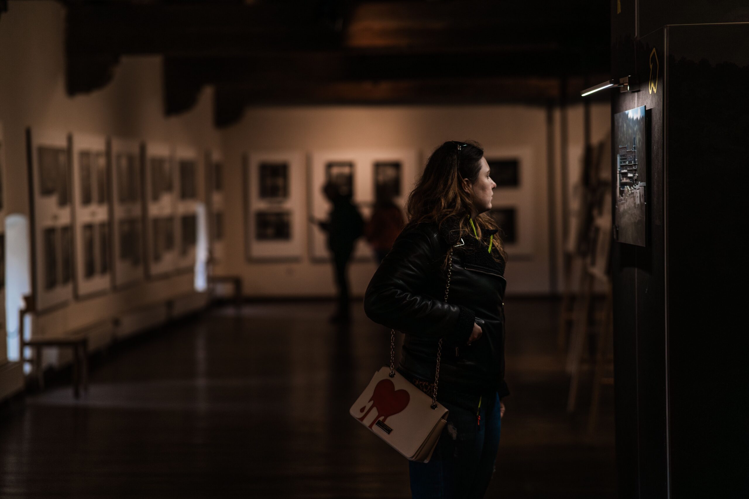 Woman viewing photographs displayed on the walls of a museum or gallery.