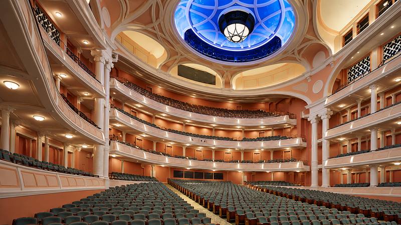 Alt Text: Elegant theater auditorium with multiple balconies, rows of green seats, and a decorative blue domed ceiling.