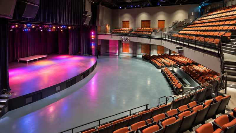 Interior of Charleston Music Hall with tiered seating, stage curtains, and colorful performance lighting.