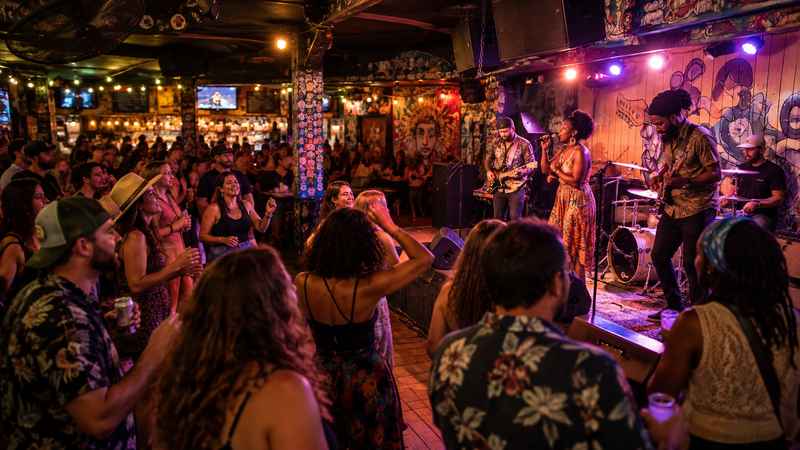 Live band performing at Charleston Pour House with a crowd gathered near the stage under colorful indoor lighting.