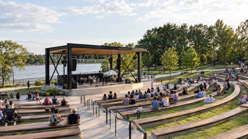 Riverfront Park Performance Pavilion with tiered seating, a riverside stage, and visitors gathered outdoors.