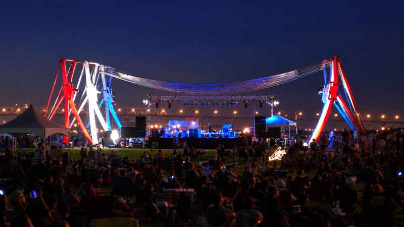 Nighttime concert at Riverfront Park Performance Pavilion with an illuminated stage and audience gathered on the lawn.